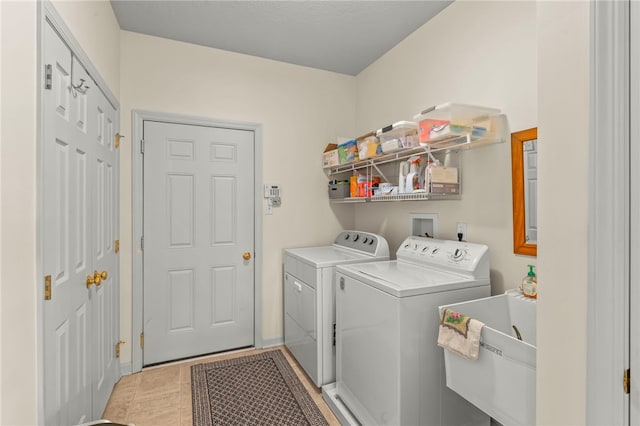 laundry area featuring light tile patterned flooring, washing machine and dryer, and sink