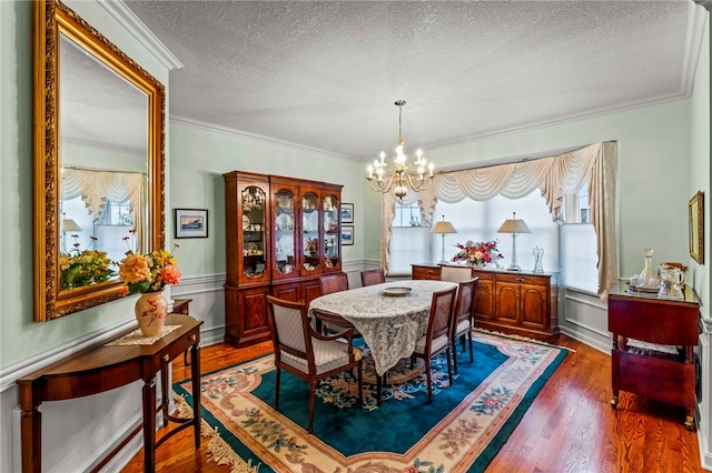 dining space with a textured ceiling, dark hardwood / wood-style floors, crown molding, and a notable chandelier