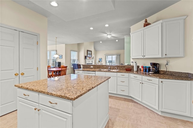 kitchen featuring kitchen peninsula, white cabinets, a kitchen island, and sink