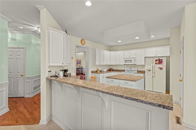 kitchen with light stone countertops, white appliances, and kitchen peninsula