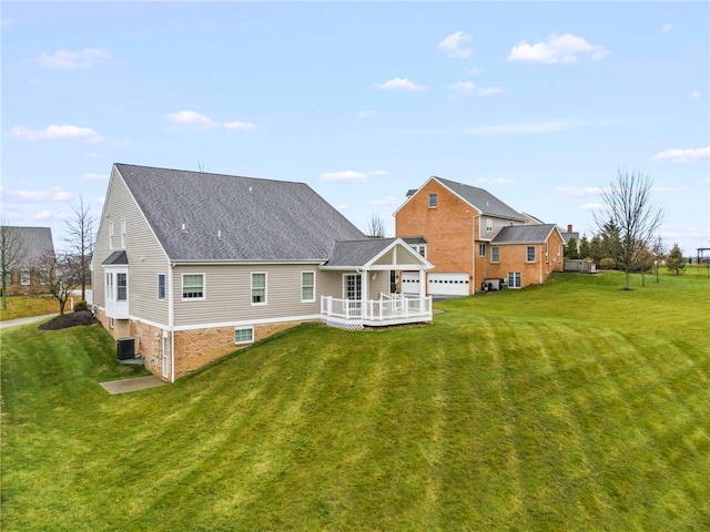 rear view of property with a lawn, cooling unit, and a garage