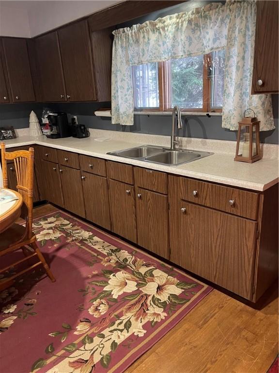 kitchen with dark brown cabinetry, sink, and light hardwood / wood-style flooring