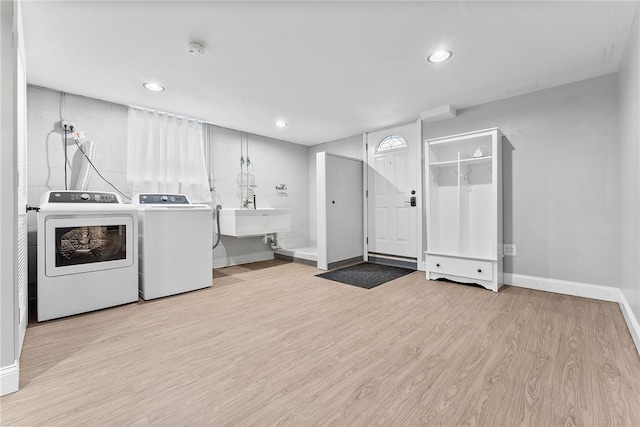 washroom featuring washing machine and dryer, sink, and light hardwood / wood-style floors