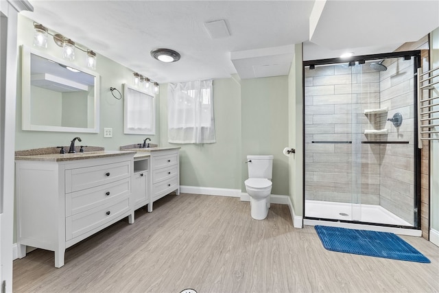 bathroom featuring hardwood / wood-style floors, vanity, toilet, and a shower with door