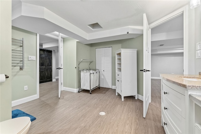 bathroom with hardwood / wood-style floors, vanity, toilet, and radiator heating unit