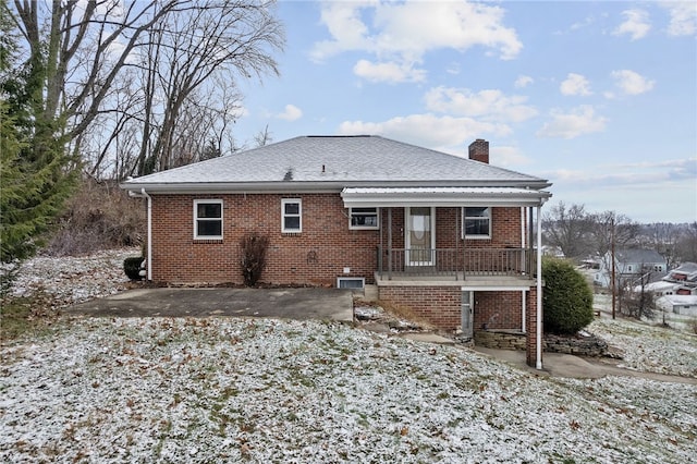 back of property with a shingled roof, a chimney, a patio area, a porch, and brick siding