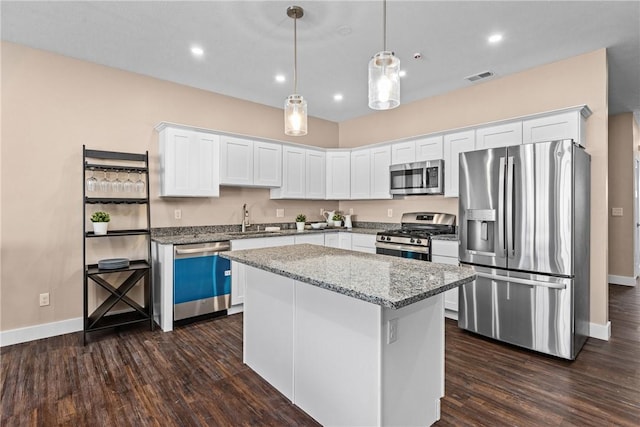 kitchen featuring white cabinets, appliances with stainless steel finishes, a center island, and decorative light fixtures