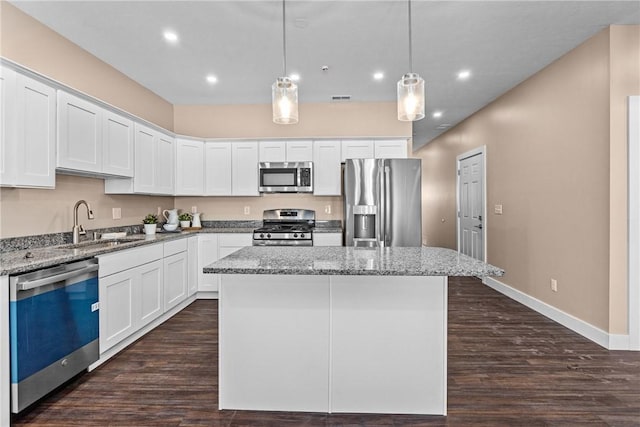 kitchen featuring light stone countertops, a center island, white cabinets, and appliances with stainless steel finishes