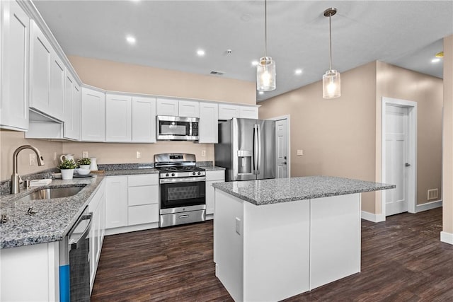 kitchen with white cabinets, hanging light fixtures, a kitchen island, and stainless steel appliances