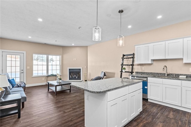 kitchen with a center island, white cabinets, sink, stainless steel dishwasher, and decorative light fixtures