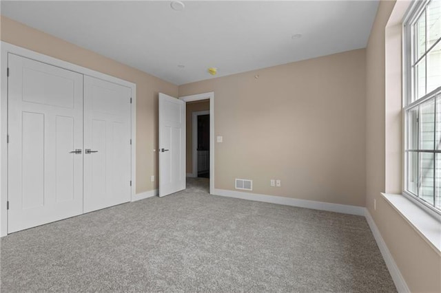 unfurnished bedroom featuring light carpet and a closet