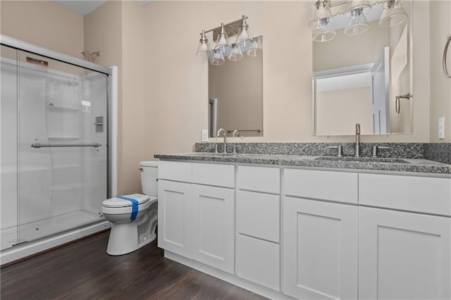 bathroom with vanity, toilet, a shower with shower door, and wood-type flooring