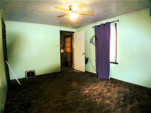 spare room with dark carpet, ceiling fan, and crown molding