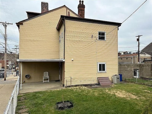 back of house with a yard and central AC