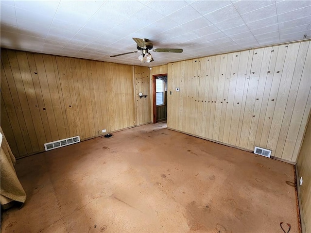 spare room featuring ceiling fan and wood walls