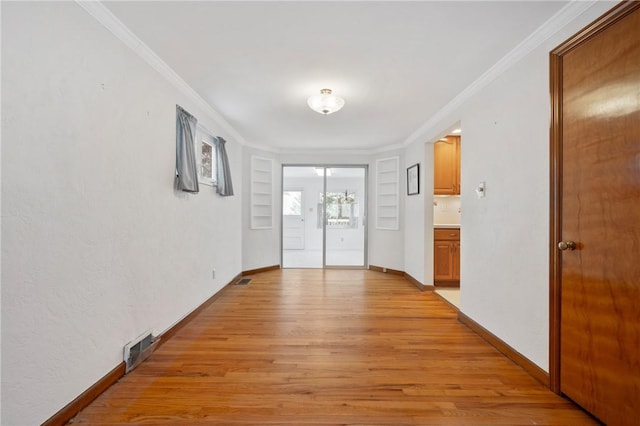 hallway with built in shelves, light hardwood / wood-style floors, and crown molding