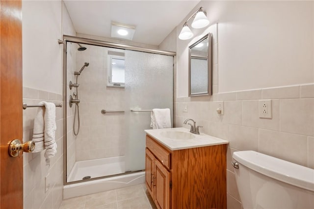 bathroom with vanity, toilet, a shower with door, and tile walls