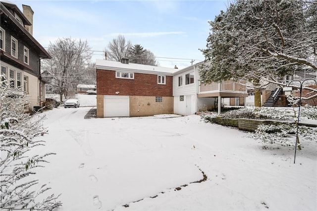 snow covered house featuring a garage