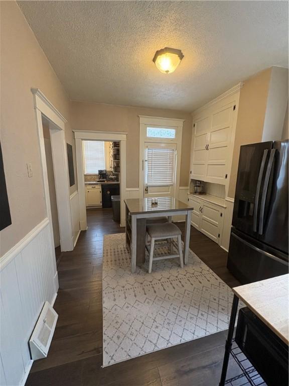 kitchen with refrigerator with ice dispenser, dark hardwood / wood-style flooring, a textured ceiling, and white cabinetry