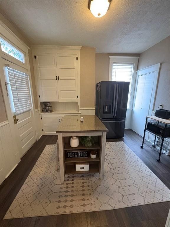 kitchen featuring white cabinetry, black fridge with ice dispenser, dark hardwood / wood-style floors, and a textured ceiling