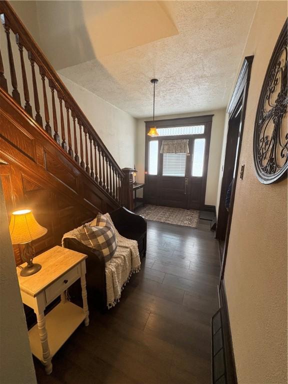 foyer entrance with a textured ceiling and dark wood-type flooring