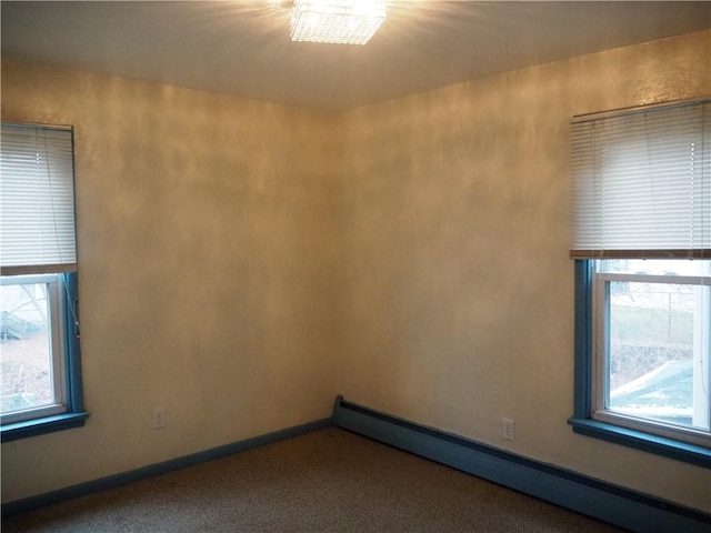 unfurnished room featuring carpet flooring, a baseboard radiator, a wealth of natural light, and a chandelier