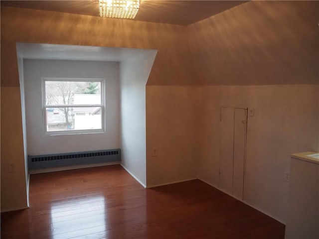 bonus room featuring a notable chandelier, wood-type flooring, radiator heating unit, and vaulted ceiling