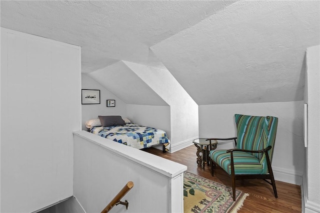 bedroom featuring dark hardwood / wood-style floors, a textured ceiling, and vaulted ceiling