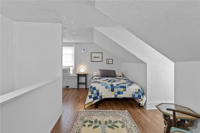 bedroom with hardwood / wood-style flooring, a textured ceiling, and vaulted ceiling