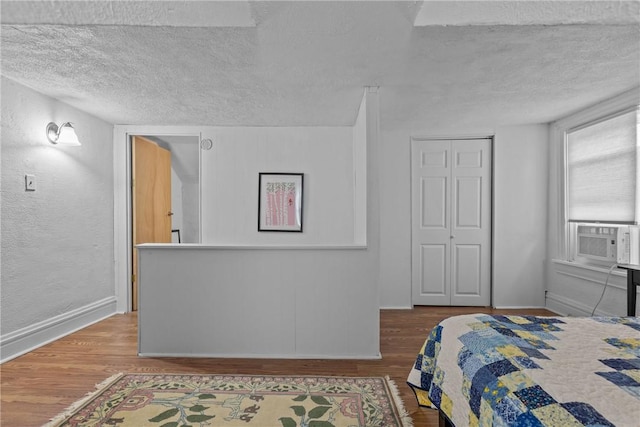 bedroom with wood-type flooring, a textured ceiling, a closet, and cooling unit