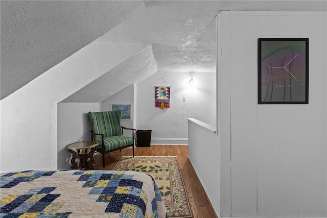 bedroom with a textured ceiling, lofted ceiling, and dark wood-type flooring