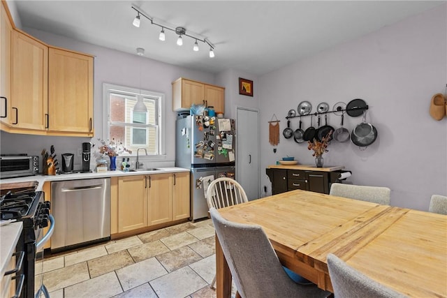 kitchen with hanging light fixtures, light brown cabinets, stainless steel appliances, and sink