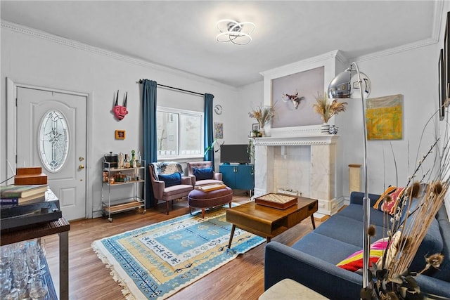 sitting room with hardwood / wood-style floors, crown molding, and a tiled fireplace