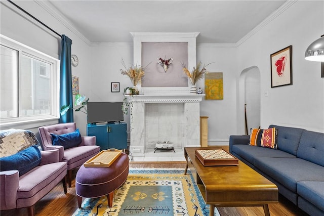 living room with wood-type flooring, ornamental molding, and a tile fireplace