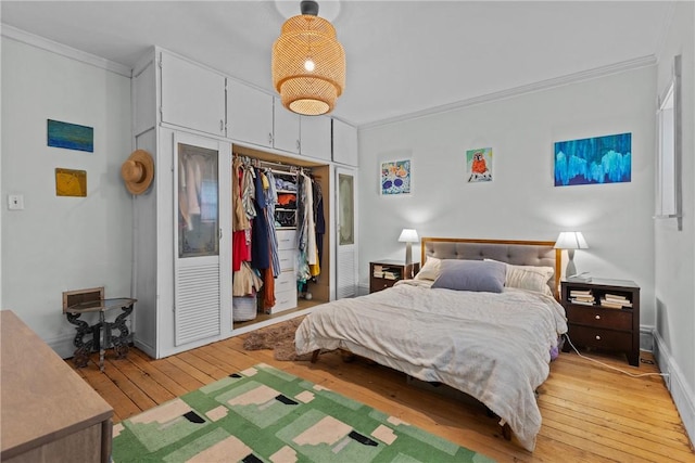 bedroom featuring light wood-type flooring, crown molding, and a closet