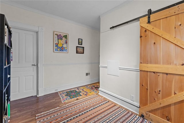 interior space with dark hardwood / wood-style flooring, a barn door, and ornamental molding