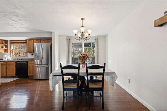 dining space with a textured ceiling, sink, dark wood-type flooring, and a chandelier