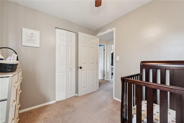 carpeted bedroom featuring a crib, a closet, and ceiling fan