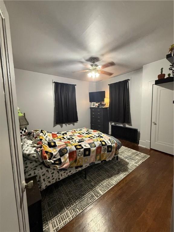 bedroom with radiator, ceiling fan, and dark hardwood / wood-style flooring