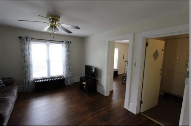 living room featuring ceiling fan and dark hardwood / wood-style floors