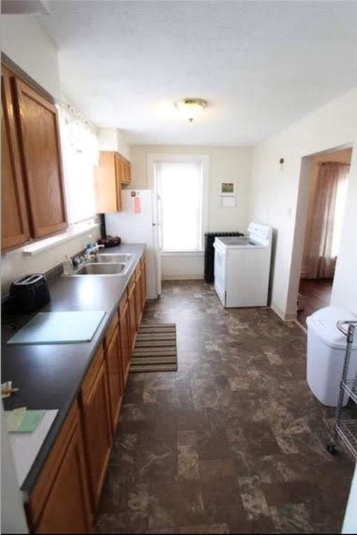 kitchen with washer / dryer, white refrigerator, and sink