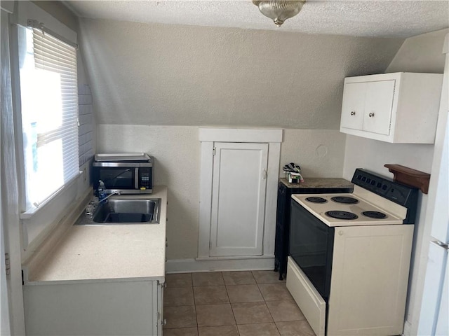 kitchen with white electric range, vaulted ceiling, white cabinetry, and light tile patterned floors