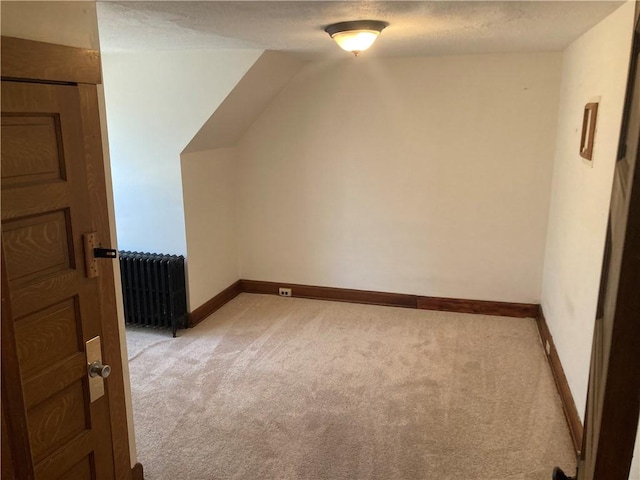 additional living space with lofted ceiling, light colored carpet, and radiator heating unit