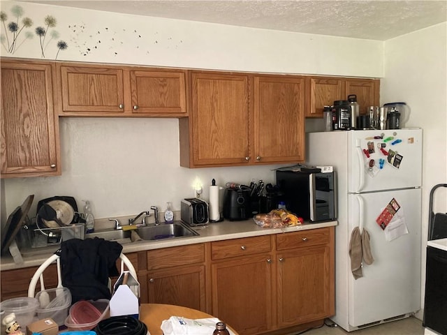 kitchen with a textured ceiling, white fridge, and sink