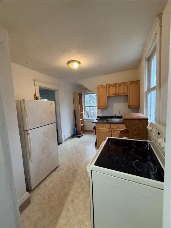 kitchen with light brown cabinets, white appliances, and sink