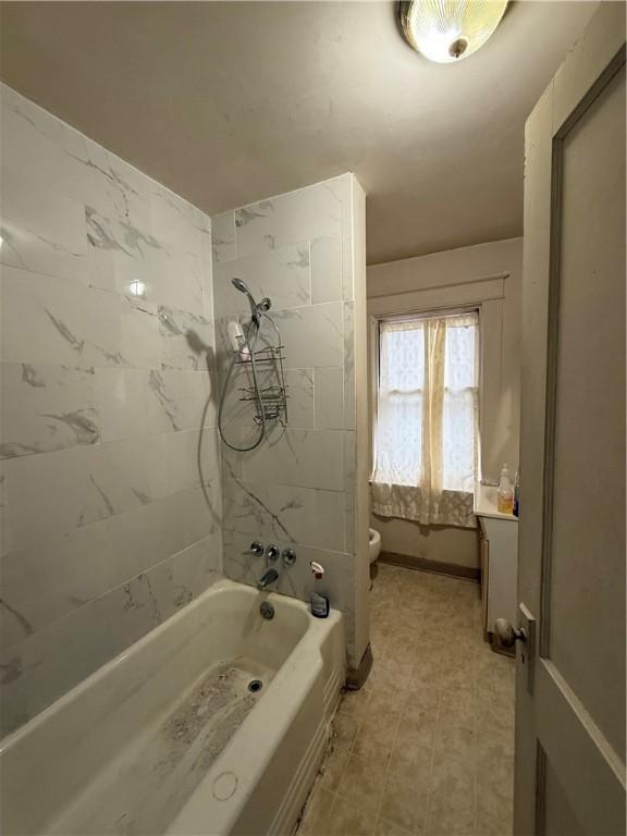 full bathroom featuring tiled shower / bath, vanity, and toilet