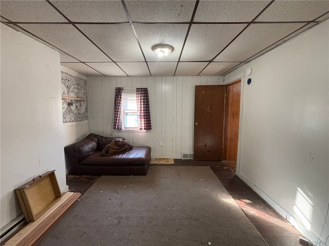 unfurnished room featuring a drop ceiling and wooden walls