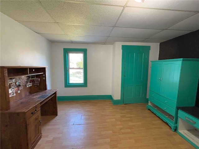 interior space featuring a paneled ceiling and light hardwood / wood-style floors