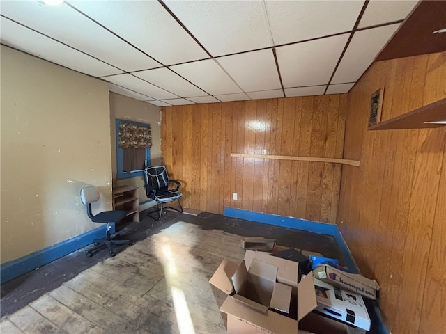 workout area with a paneled ceiling and wood walls