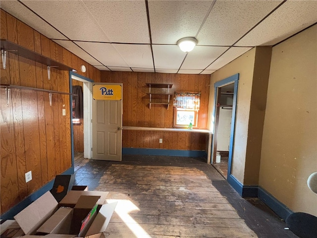 interior space featuring a drop ceiling and wood walls